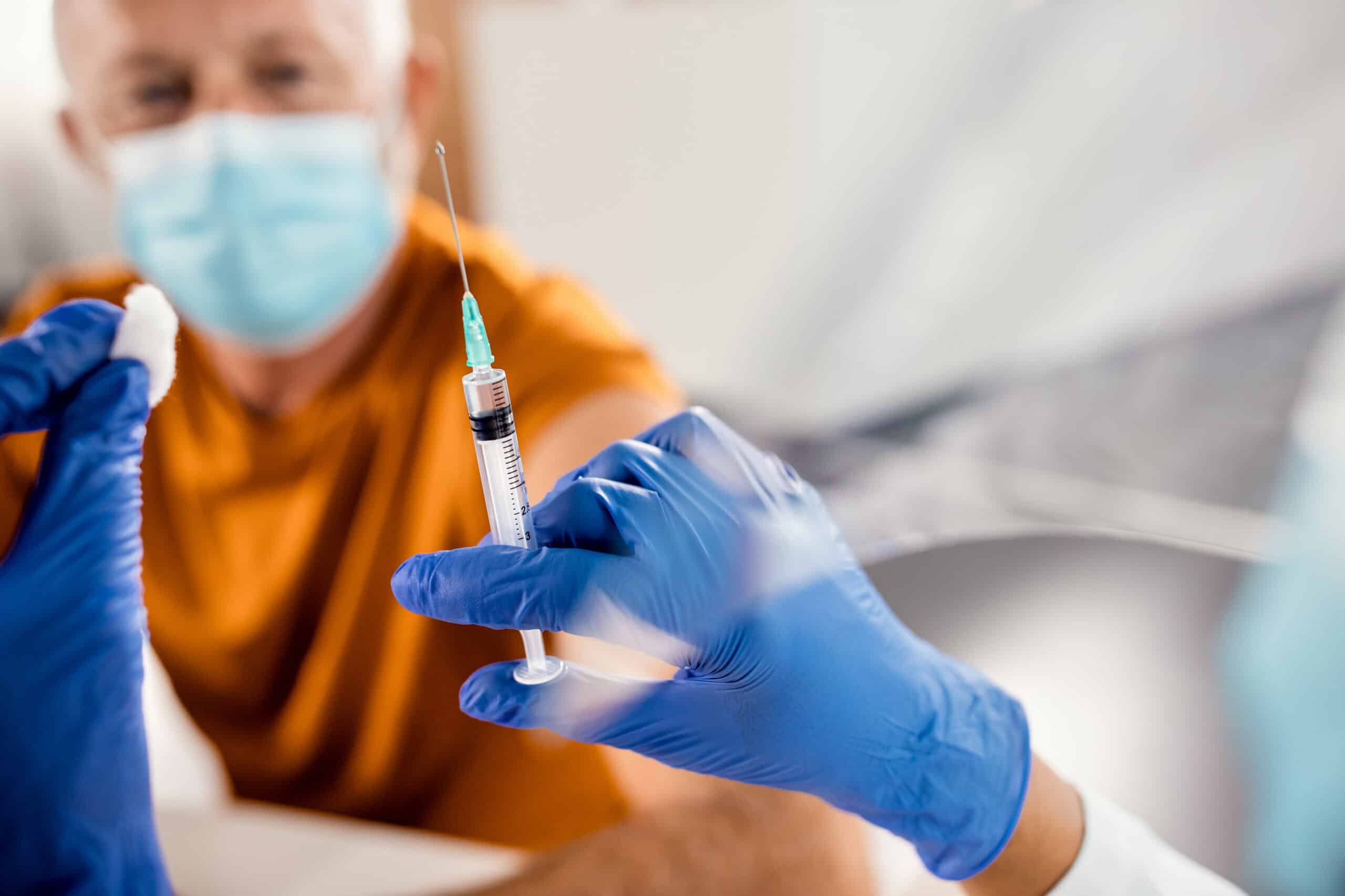 Close-up of doctor preparing vaccine for a senior patient at the